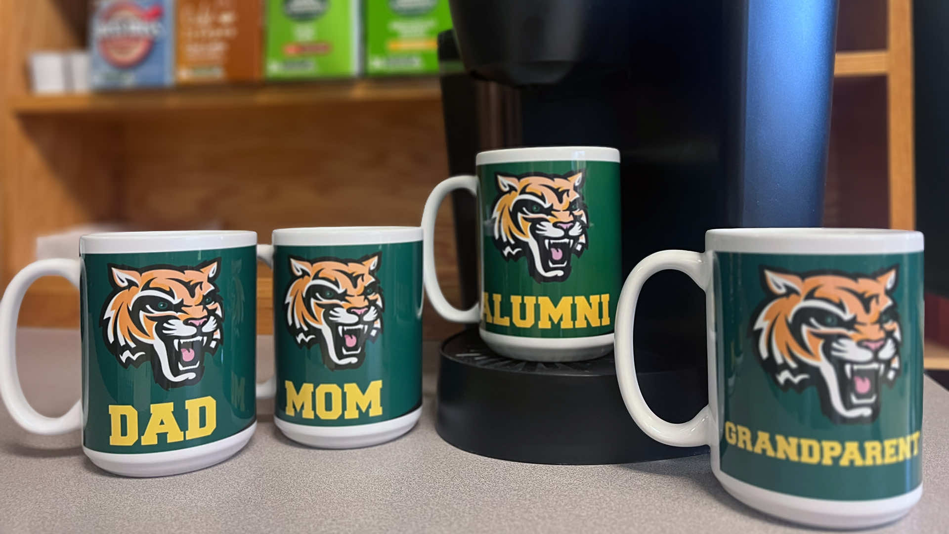 a collection of family and alumni coffee mugs displayed in front of a coffee maker